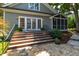 Home's back exterior features wooden stairs to a patio with white French doors and manicured landscaping at 2707 Anderson Drive Dr, Raleigh, NC 27608