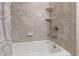 Clean, tiled bathtub and shower showcasing neutral tones, built-in shelving, and a modern shower head fixture at 2707 Anderson Drive Dr, Raleigh, NC 27608