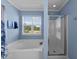 Brightly lit main bathroom features separate soaking tub and glass enclosed shower with attractive blue walls at 300 Stobhill Ln, Holly Springs, NC 27540