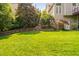 Green backyard featuring a well-kept lawn, mature trees, and meticulously landscaped surroundings at 315 Birdwood Ct, Cary, NC 27519