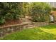 Landscaped backyard with stone retaining wall, mature plantings, and stone steps at 315 Birdwood Ct, Cary, NC 27519