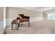 Spacious living room featuring a baby grand piano, neutral decor, large windows, and a modern chandelier at 315 Birdwood Ct, Cary, NC 27519