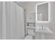Well-lit bathroom features a sleek pedestal sink, decorative storage cabinet, and a shower with a white curtain at 406 E Whitaker Mill Rd, Raleigh, NC 27608