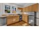 Corner kitchen featuring light wood cabinets, stainless steel appliances, and hardwood floors at 406 E Whitaker Mill Rd, Raleigh, NC 27608