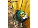 Green bicycle leaning against a bright yellow fence and loaded with fresh produce at 430 Walnut St, Cary, NC 27511