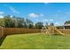 Large, green fenced backyard featuring a swing set and lush lawn at 444 Campbell Ridge Pl, Wendell, NC 27591