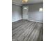 Bright living room with gray wood-look flooring, gray walls, and a white front door at 501 Morgan Ter, Burlington, NC 27217