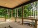 Covered porch view of wooded area with wood railing at 5027 Preacher Holmes Rd, Graham, NC 27253