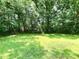 Backyard with a grassy lawn, bordered by trees, offering a private outdoor space at 525 Locust Rd, Hillsborough, NC 27278