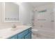 Bright bathroom with blue vanity, shower over tub, white tiled walls, and grab bars at 716 Beddingfield Dr, Knightdale, NC 27545
