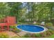 Backyard features an oval pool, mature landscaping, an a red deck at 716 Beddingfield Dr, Knightdale, NC 27545