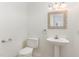 Clean powder room with a toilet, pedestal sink, decorative mirror and wall-mounted towel rack at 716 Beddingfield Dr, Knightdale, NC 27545