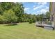 Expansive backyard with a well-maintained lawn, mature trees, and a deck with outdoor furniture at 1020 Regency Cottage Pl, Cary, NC 27518