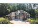 A view of a two-story brick home with a large driveway and three-car garage surrounded by mature trees at 1028 Harpers Ridge Ct, Wake Forest, NC 27587