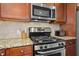 Close-up of the kitchen with stainless steel stove, granite countertops, and wooden cabinets at 10570 Evergreen Spring Pl, Raleigh, NC 27614