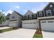 New townhomes featuring attached garages, manicured lawn, and traditional curb appeal at 1218 Tredenham Way, Durham, NC 27703