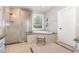 Bright bathroom with walk-in shower, soaking tub, and a large window offering natural light and views at 1502 Spring Overlook Ln, Hillsborough, NC 27278