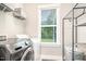 Bright laundry room with modern machines, wire rack shelving, and natural light from a window at 1502 Spring Overlook Ln, Hillsborough, NC 27278