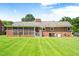 Backyard view showcasing the home's well-kept lawn and exterior brick, with screened-in porch and AC units at 1702 Pinecrest St, Burlington, NC 27215