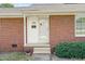 Welcoming front entrance of a brick home with a storm door and well-maintained landscaping at 1702 Pinecrest St, Burlington, NC 27215