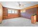 Carpeted living room with wood paneling, a brick accent wall, built-in shelving and a window at 1702 Pinecrest St, Burlington, NC 27215