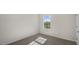 A sunlit bedroom with neutral carpet, blank walls, and a window with outdoor views at 195 Babbling Creek Dr, Youngsville, NC 27596