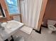 Well-lit bathroom featuring classic fixtures, including a pedestal sink, toilet, shower, and black and white floors at 207 Wood Cir, Chapel Hill, NC 27514