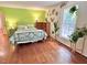 Bright bedroom with hardwood floors, plant accents, and a bed featuring a green and white leaf pattern duvet cover at 207 Wood Cir, Chapel Hill, NC 27514