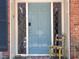 Inviting light blue front door with sidelights, door mat and decorative chair at 207 Wood Cir, Chapel Hill, NC 27514
