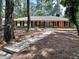 Charming brick home featuring a stone walkway, lush landscaping, and a bright blue front door at 207 Wood Cir, Chapel Hill, NC 27514