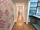 Long hallway featuring wood floors connecting various rooms, accented by a colorful quilt and a built-in shelf at 207 Wood Cir, Chapel Hill, NC 27514