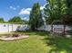 Serene backyard showcasing a fire pit, a wooden swing, lush greenery, and a white privacy fence at 229 Hocutt Farm Dr, Clayton, NC 27527