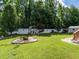 Extensive backyard featuring a fire pit, a wooden swing set, lush greenery, and a white privacy fence at 229 Hocutt Farm Dr, Clayton, NC 27527