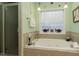 Relaxing bathroom featuring a luxurious jetted tub, tile surround, and elegant lighting fixtures at 229 Hocutt Farm Dr, Clayton, NC 27527