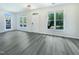 Sunlit living room with grey floors, a front door, and views of the outdoors through windows at 27 Stonewall Way, Durham, NC 27704