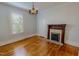 Cozy bedroom featuring a decorative fireplace, hardwood floors, and natural light from the window at 29 Oak St, Roxboro, NC 27573