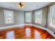 Spacious bedroom featuring hardwood floors, three windows, a ceiling fan, and neutral walls at 29 Oak St, Roxboro, NC 27573