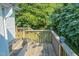 Wooden deck featuring wood railings, greenery, and an outdoor light fixture at 29 Oak St, Roxboro, NC 27573
