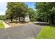 Exterior of white two-story home featuring mature landscaping and ample parking on blacktop driveway at 347 W Trade St, Burlington, NC 27217