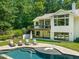 Beautiful backyard view with a large pool, stone patio, lounge seating, and lush greenery, ideal for relaxation and entertaining at 3707 Stonegate Dr, Chapel Hill, NC 27516