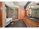 Luxurious bathroom boasts a soaking tub, glass shower with brick accent wall, and wooden cabinets with granite countertops at 3707 Stonegate Dr, Chapel Hill, NC 27516