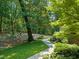 Landscaped front yard with lush greenery and a stone walkway leading to a charming home surrounded by mature trees at 3707 Stonegate Dr, Chapel Hill, NC 27516
