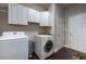 Functional laundry room features a washer, dryer, overhead cabinets, and dark wood-look flooring at 413 Great Smokey Mountain Dr, Mebane, NC 27302