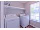 Bright laundry room with a white washer, dryer, and a convenient shelf above at 4928 Silverdene St, Raleigh, NC 27616