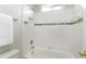 A white bathtub and shower with a decorative accent tile and fixtures at 500 Walcott Way, Cary, NC 27519