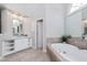 Bright bathroom with a soaking tub, walk-in shower, white cabinetry, and a large mirror at 500 Walcott Way, Cary, NC 27519
