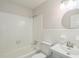 Bright bathroom features a shower-tub combo, toilet, and vanity with a round mirror at 605 Sagefield Way, Henderson, NC 27537