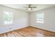 Well-lit bedroom with hardwood floors, ceiling fan, and two windows bringing in natural light at 605 Sagefield Way, Henderson, NC 27537