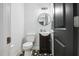 Well-lit half bathroom with black and white tile, round mirror, and pedestal sink at 605 W Holt St, Mebane, NC 27302