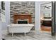 Bright bathroom featuring a clawfoot tub next to a stone fireplace and an ensuite bedroom at 605 W Holt St, Mebane, NC 27302